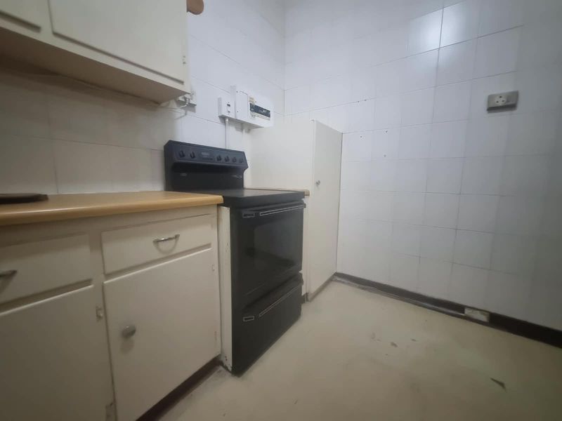 A functional kitchen space featuring built-in cabinetry, a freestanding oven, and tiled wall finishes, offering potential for modernization and renovation.