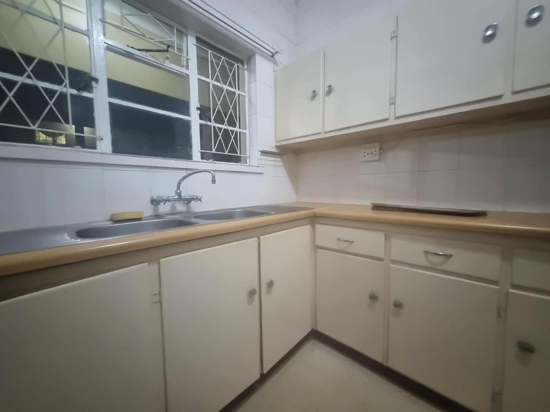 A functional kitchen featuring laminate countertops, built-in cabinetry, and a double bowl stainless steel sink with a window overlooking the exterior.
