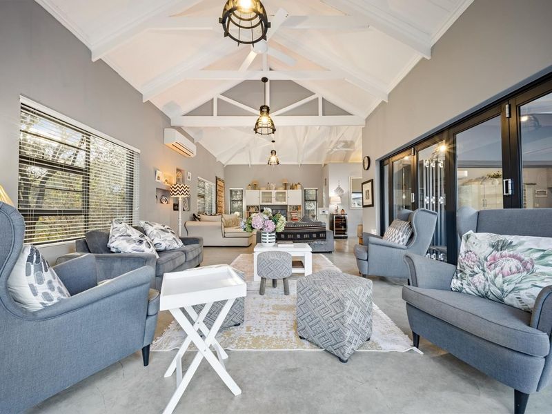 Spacious living room featuring a high vaulted ceiling with exposed trusses, polished concrete flooring, and large aluminium sliding doors leading to the exterior.