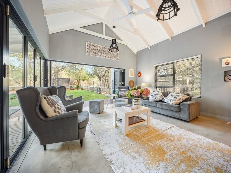 Spacious living room featuring a vaulted ceiling with exposed rafters, polished concrete floors, and large bi-fold doors opening to the garden.
