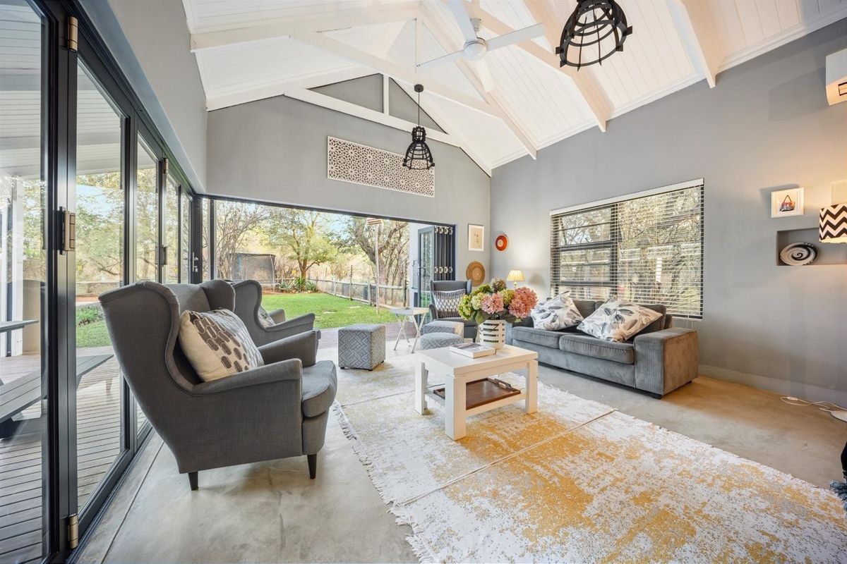 Spacious living room featuring a vaulted ceiling with exposed rafters, polished concrete floors, and large bi-fold doors opening to the garden.