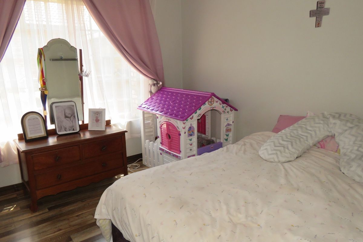 A bedroom featuring laminate flooring and natural light through a window with curtain rails.