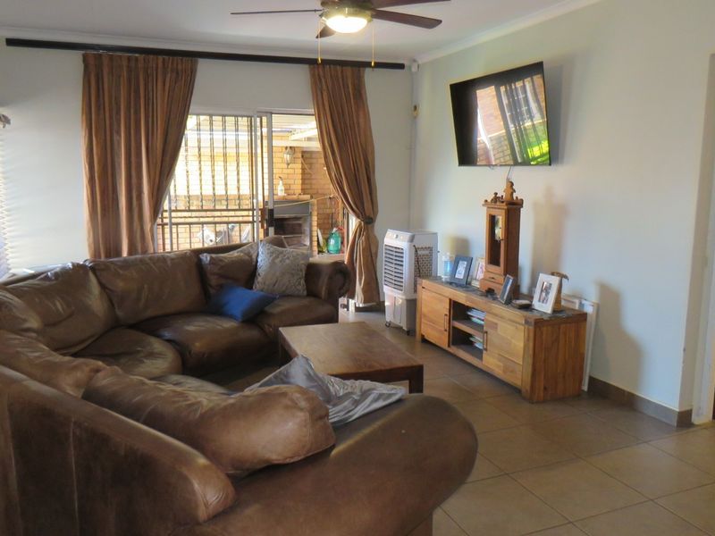 A functional living room featuring tiled flooring, a ceiling fan, and a sliding glass door providing access to an outdoor patio area.