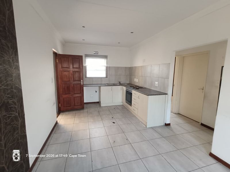 A functional kitchen featuring tiled flooring, built-in cabinetry, a hob, and an oven, offering a clean canvas for potential updates.