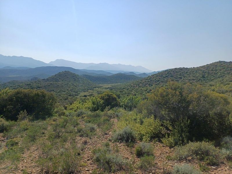 A scenic landscape view showcasing the natural terrain, rolling hills, and distant mountain ranges characteristic of the farm property.