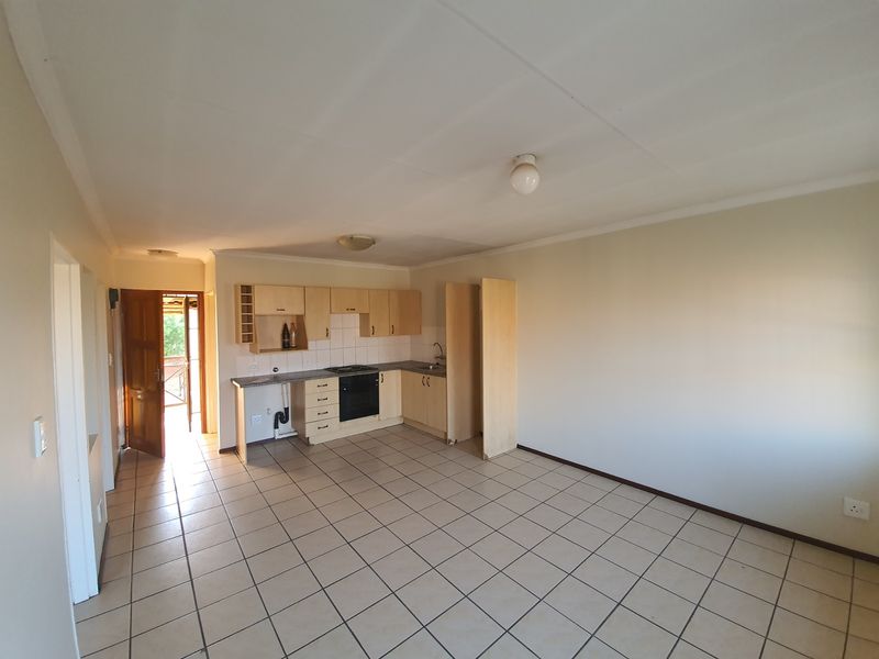 Open plan kitchen and living area featuring tiled flooring, built-in cabinetry, and integrated oven, offering a blank canvas for renovation.