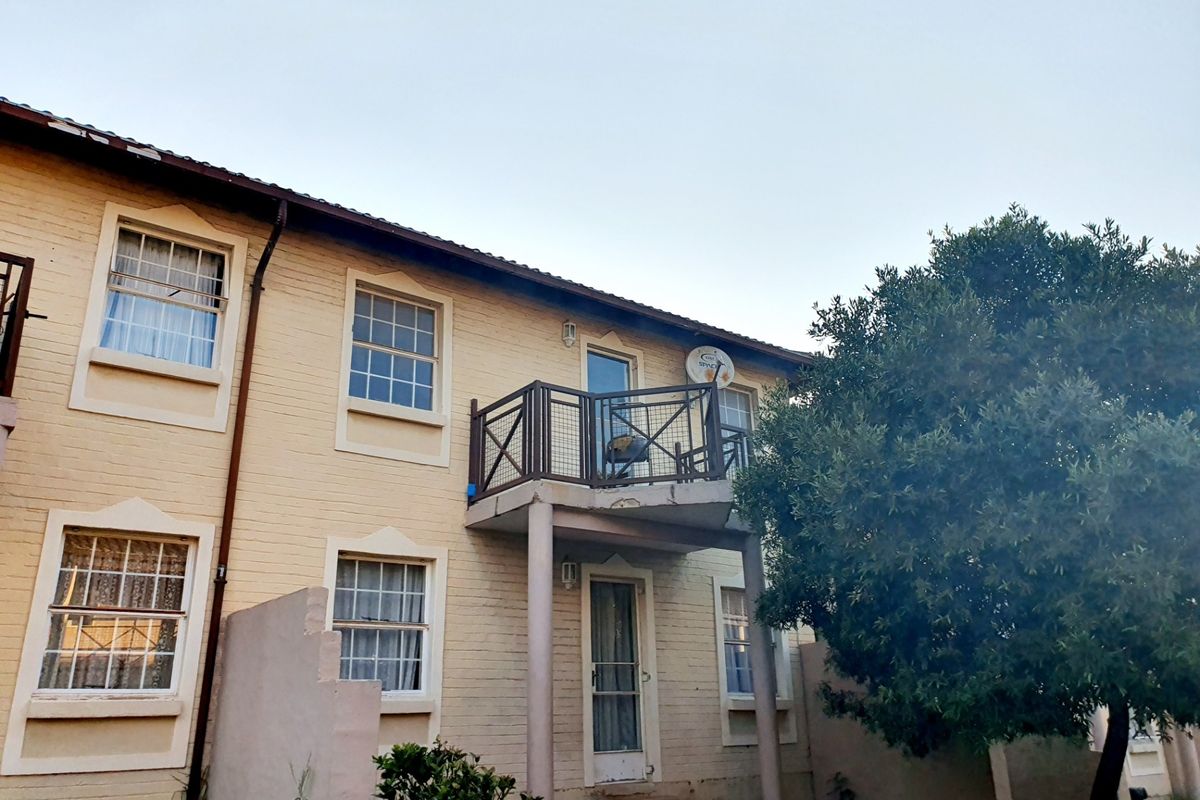Rear elevation of a townhouse featuring a brick facade, a small balcony with metal railings, and traditional sash windows.