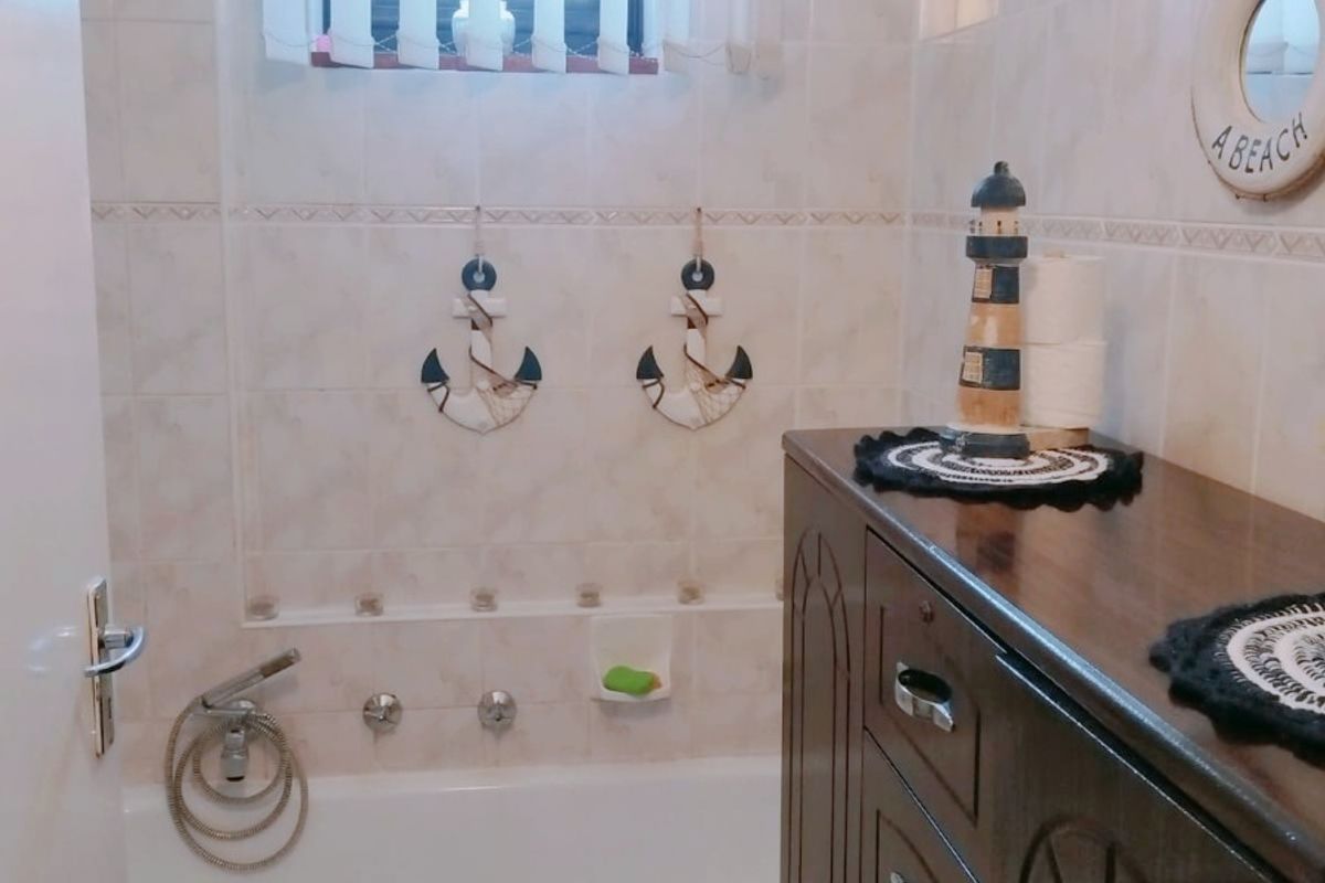 A functional bathroom featuring a bathtub with a shower mixer, tiled walls, and tiled flooring, providing a clean and practical space.