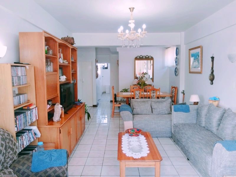 Open plan living and dining area featuring tiled flooring and a central chandelier, providing a functional and connected space for daily living.