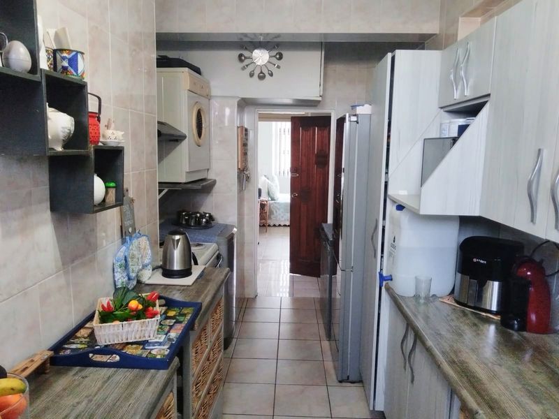 A functional galley-style kitchen featuring tiled walls, tiled flooring, and built-in cabinetry with laminate countertops, providing efficient workspace and storage.