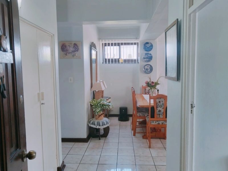 A dining area featuring tiled flooring, a built-in cupboard, and a window with security bars, providing a functional space for meals.