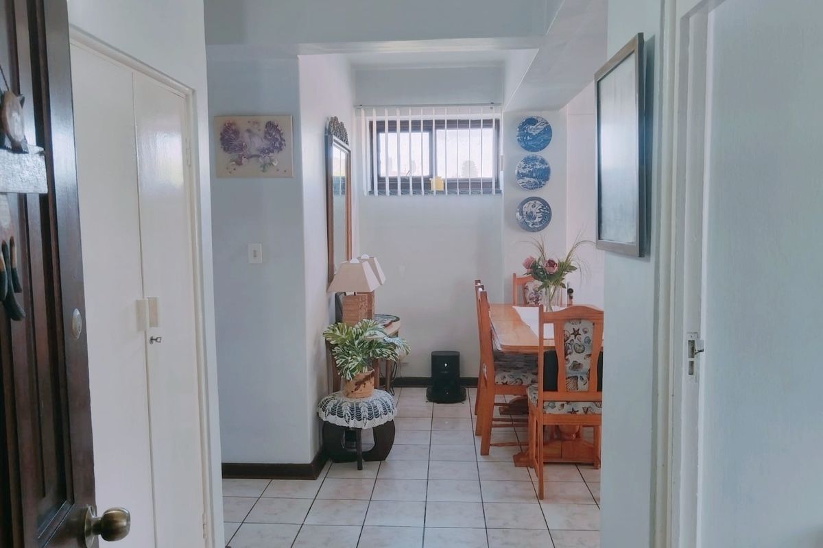 A dining area featuring tiled flooring, a built-in cupboard, and a window with security bars, providing a functional space for meals.