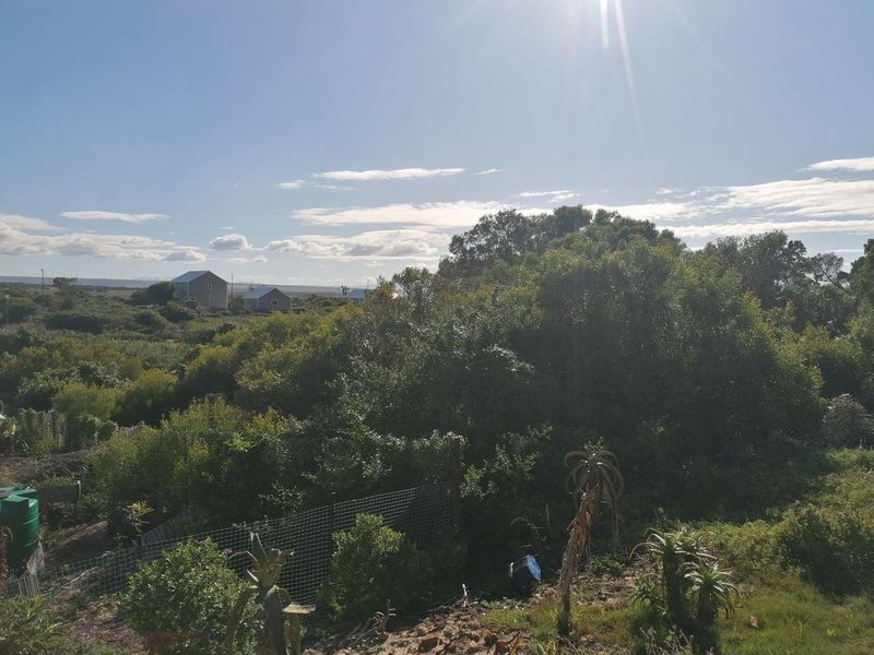 A scenic view of the surrounding landscape featuring indigenous vegetation, wire fencing, and a water storage tank on the property.