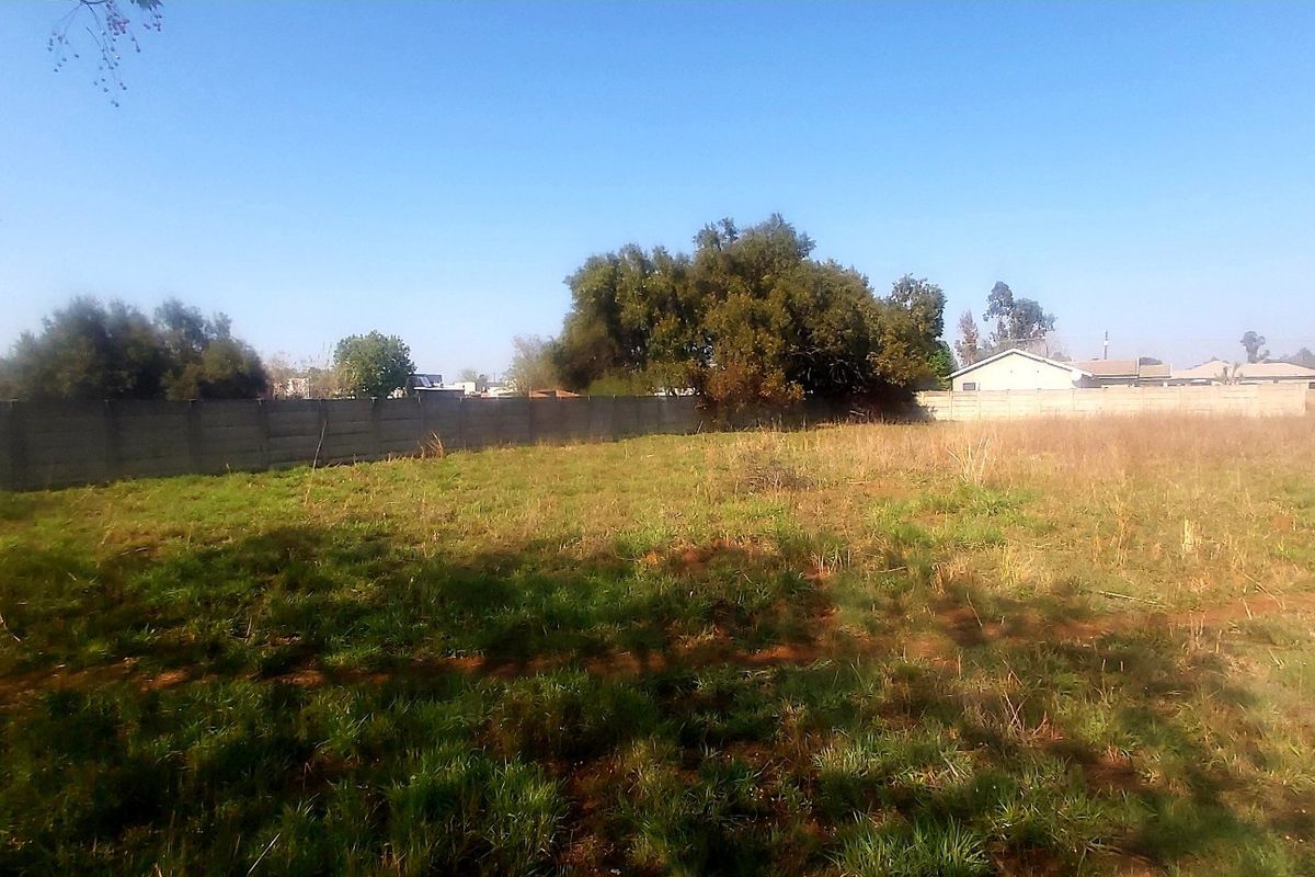 A vacant residential plot featuring a precast concrete boundary wall and natural grass coverage.