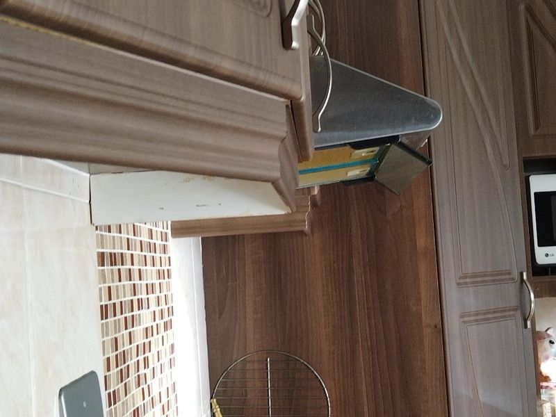A kitchen corner featuring dark wood cabinetry, a granite countertop, an electric hob, and a mosaic tile backsplash.