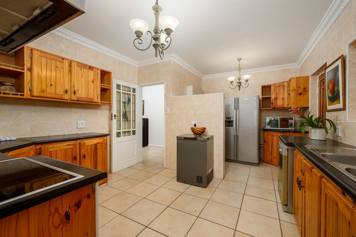 Spacious kitchen featuring traditional wooden cabinetry, tiled walls and flooring, double sink, and built-in extractor fan, offering a functional layout with ample storage.