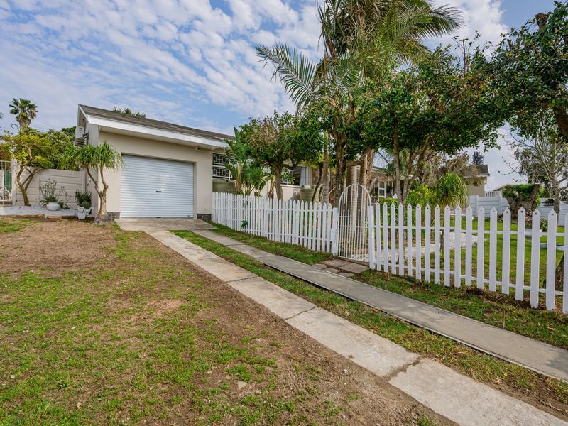 Front exterior view of the property featuring a single garage, concrete driveway, and a white picket fence enclosing the front garden area.