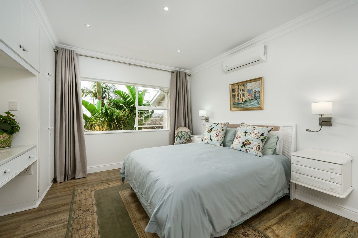 A well-maintained bedroom featuring built-in cabinetry, laminate flooring, recessed lighting, and a split-system air conditioner, offering a clean and comfortable living space.
