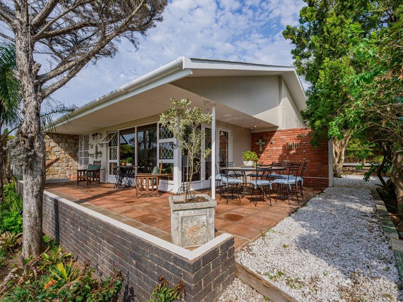 A spacious covered patio featuring tiled flooring, stone and brick accents, and direct access to the home through large sliding glass doors.