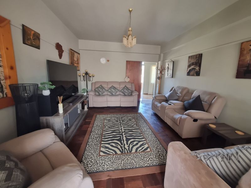 A comfortable living room featuring classic parquet flooring and a central ceiling light fixture, providing a warm and inviting space.