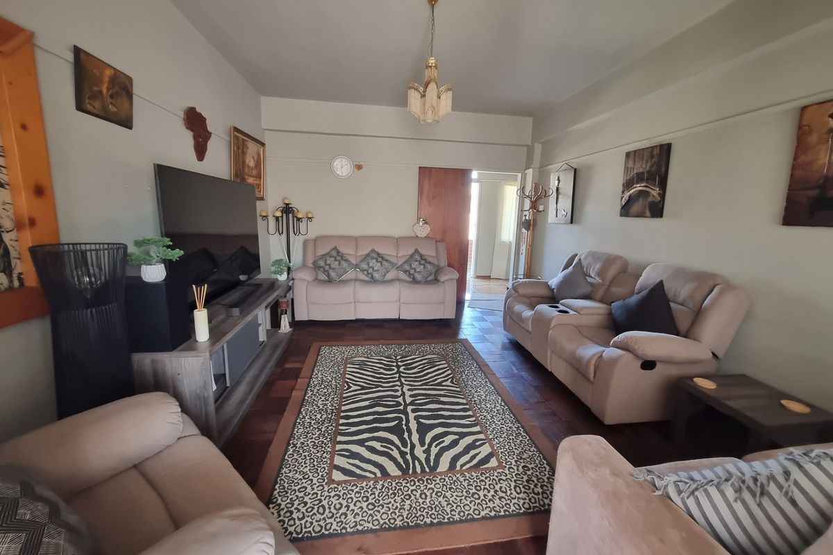 A comfortable living room featuring classic parquet flooring and a central ceiling light fixture, providing a warm and inviting space.