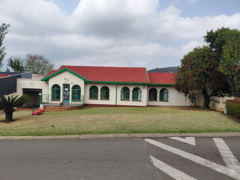 Front elevation of a single-story house featuring a red tiled roof, arched windows with security bars, and an attached garage.