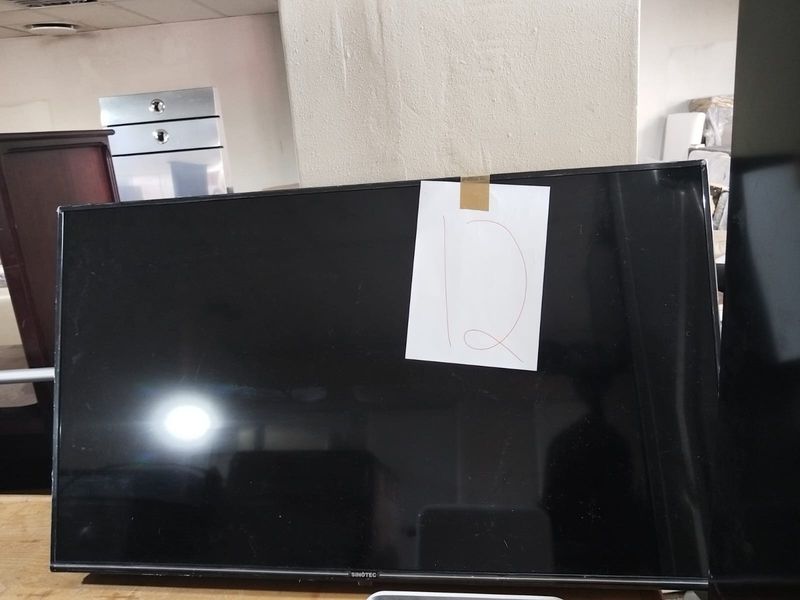 A close-up view of a television screen with a paper label attached, showing no significant architectural features of the property.