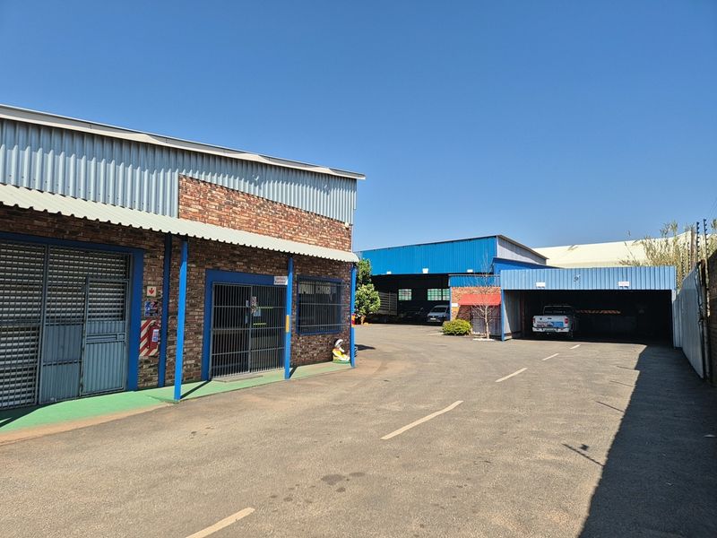 Industrial property exterior featuring a combination of face brick and corrugated metal cladding with a paved driveway and secure access points.