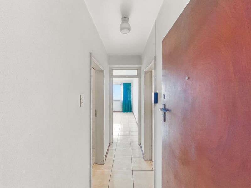 A bright, tiled hallway leading from the main entrance toward an open living area with natural light.