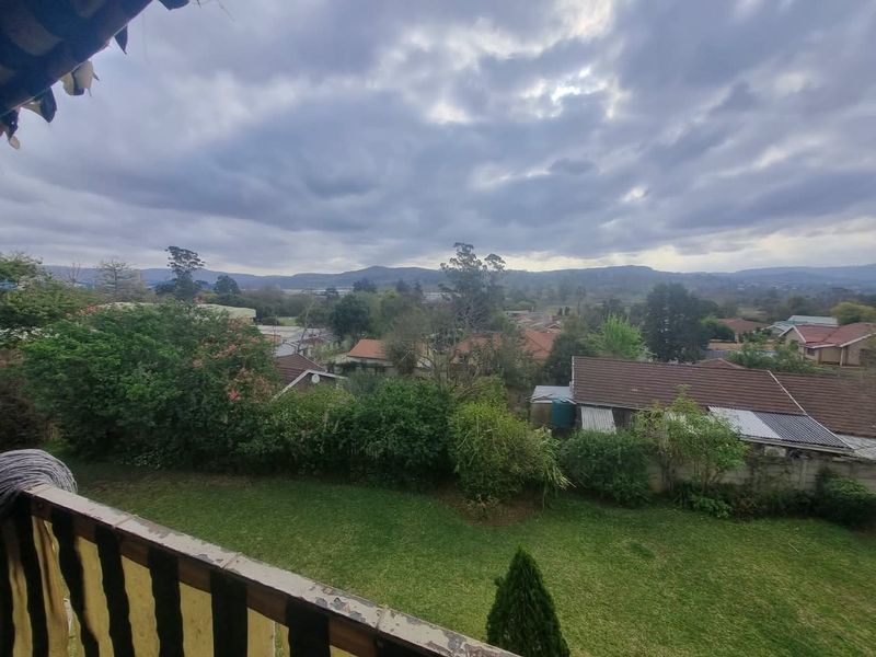 Elevated view overlooking a residential neighborhood and surrounding landscape, captured from a balcony with a weathered railing.