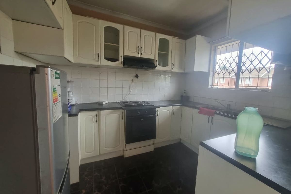 A functional kitchen featuring built-in cabinetry, a hob, oven, extractor fan, and tiled backsplash, offering potential for modernization and aesthetic updates.