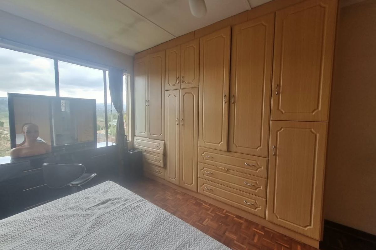 Bedroom featuring extensive built-in wooden cabinetry, parquet flooring, and a large window providing natural light and exterior views.