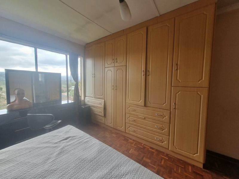 Bedroom featuring extensive built-in wooden cabinetry, parquet flooring, and a large window providing natural light and exterior views.