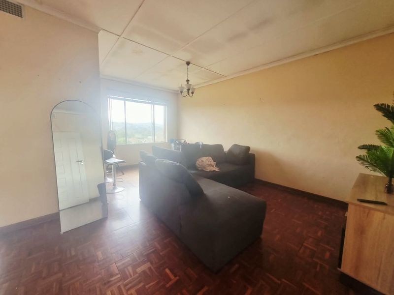 A living room featuring traditional parquet flooring and a ceiling with tile finishes, offering a blank canvas for potential renovation and modernization.