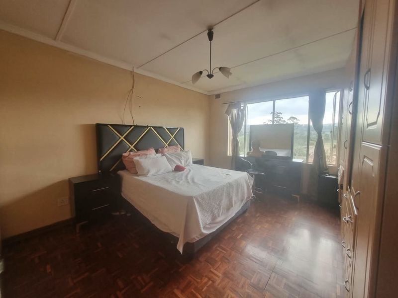 A bedroom featuring parquet flooring, built-in cupboards, and large windows providing natural light and exterior views.