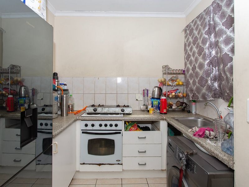 Compact kitchen featuring built-in oven, gas hob, stainless steel sink, and laminate countertops with tiled backsplash.