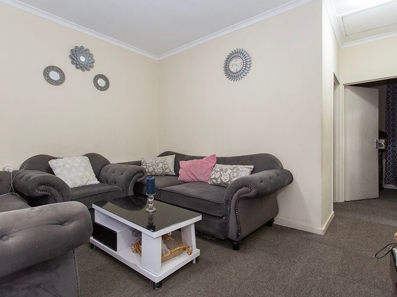 A living room area featuring neutral wall finishes, carpeted flooring, and decorative ceiling cornicing.