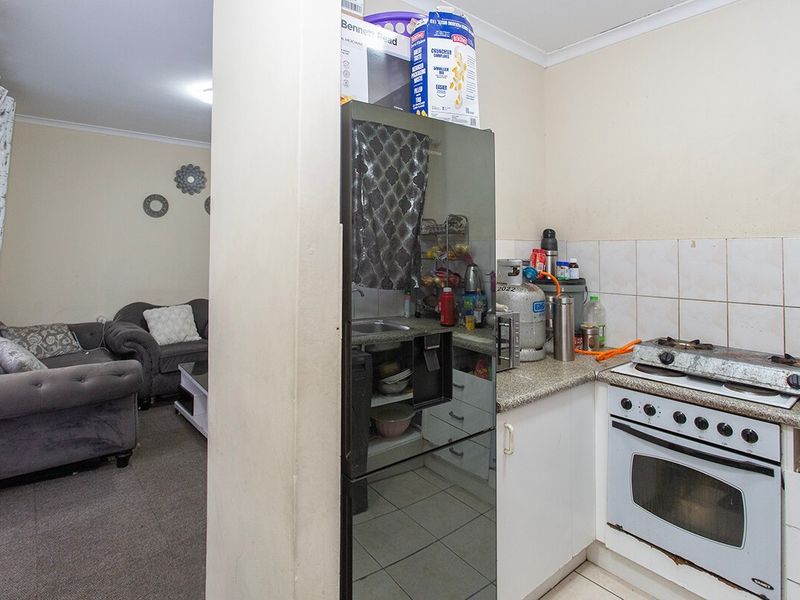 Open-plan kitchen area featuring a gas hob, built-in oven, granite countertops, and tiled backsplash, seamlessly connecting to the adjacent living space.