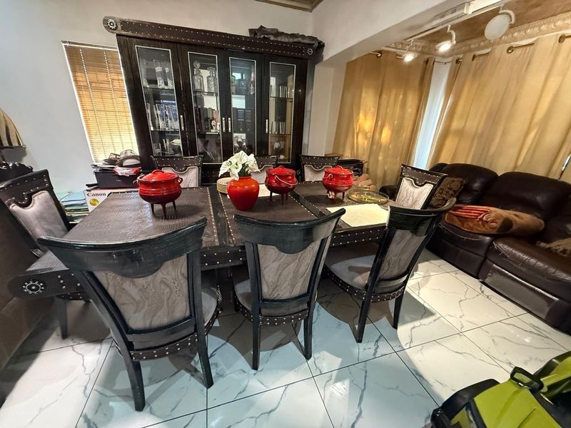 Open plan dining and living area featuring polished marble-look floor tiles, decorative ceiling cornices, and a large built-in display cabinet.