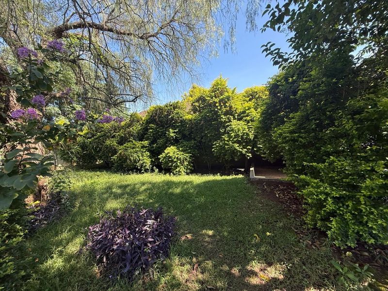 A lush, private garden area featuring mature trees, established shrubbery, and a well-maintained lawn, providing a serene outdoor space.