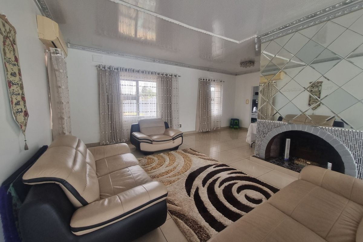Spacious living room featuring tiled flooring, a decorative mirrored fireplace surround, and a split system air conditioner.