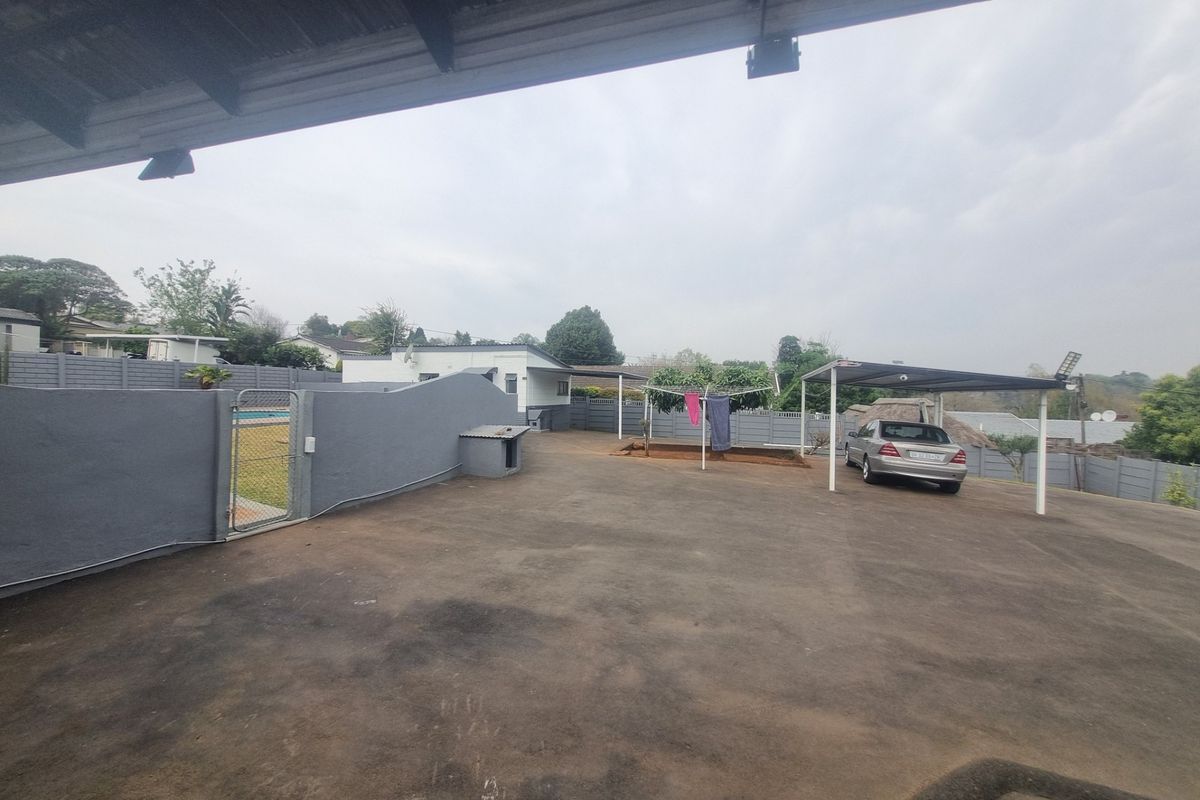 Spacious paved rear yard featuring a carport, perimeter walling, and access to the swimming pool area.