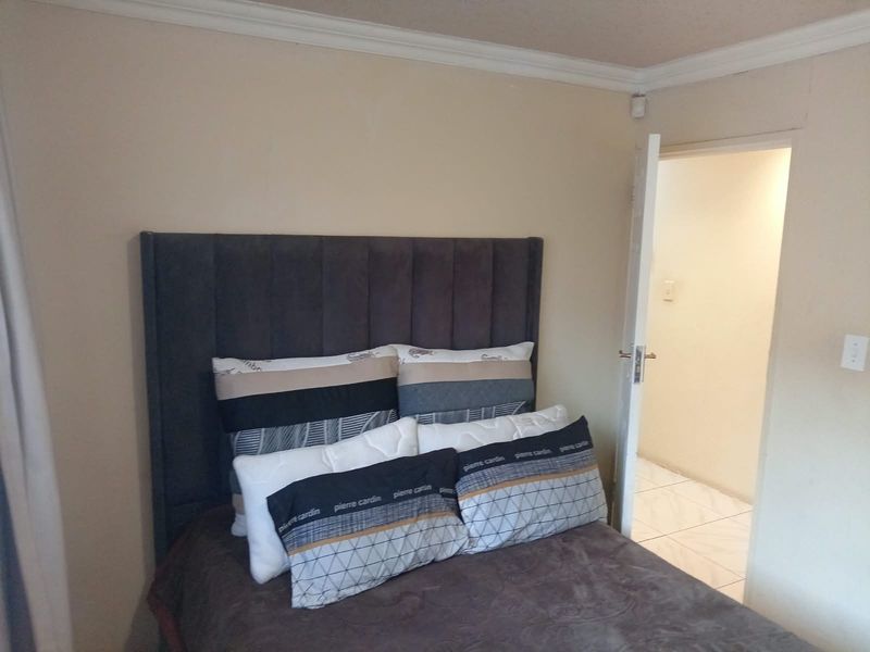 A bedroom featuring neutral wall tones and crown molding, with an adjacent hallway visible through the open doorway.