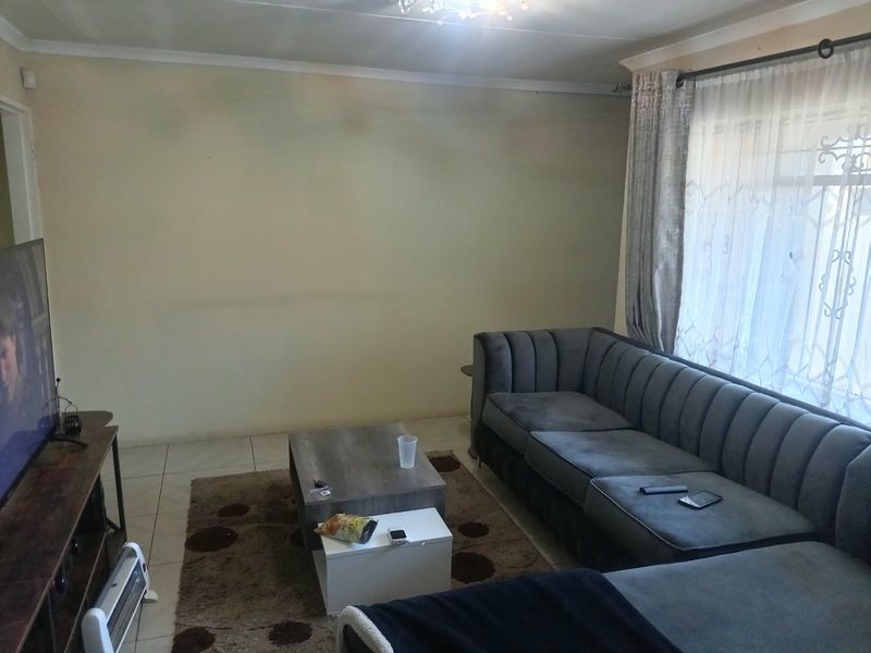 A living room featuring tiled flooring and coved ceilings, offering a functional space ready for cosmetic updates and personalization.