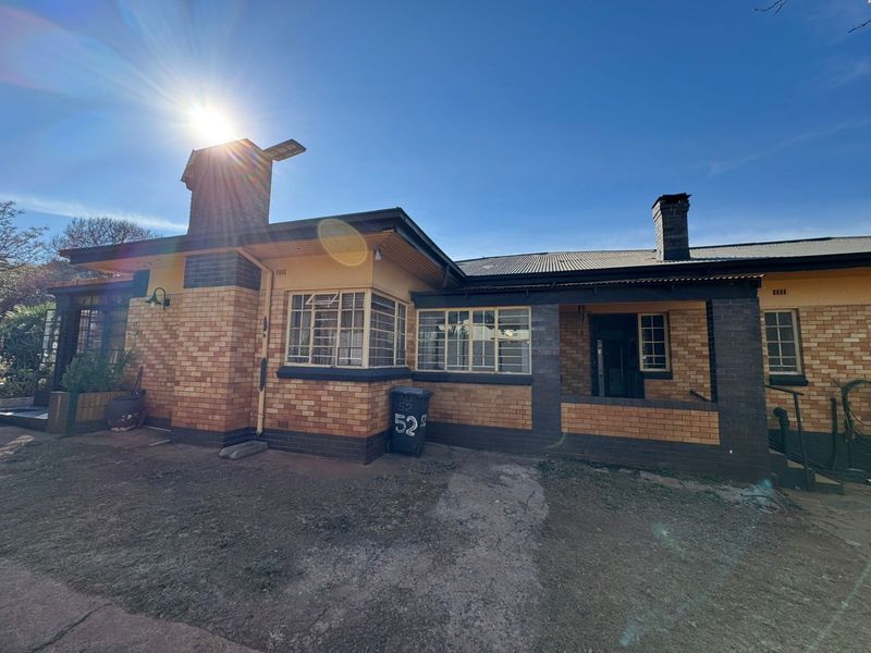 Front elevation of a traditional brick house featuring a covered porch, corrugated metal roofing, and classic steel-framed windows.