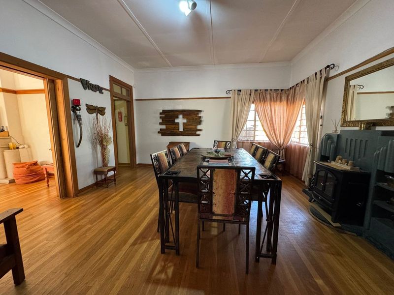 Spacious dining room featuring original hardwood flooring, a built-in wood-burning fireplace, and classic timber door frames with traditional picture rail detailing.