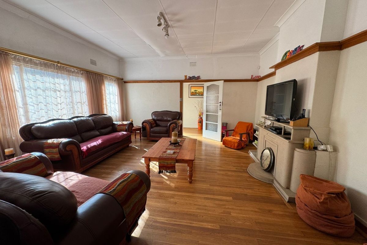 Spacious living room featuring polished hardwood flooring, a central fireplace, and classic picture rail detailing, offering a warm and inviting atmosphere.