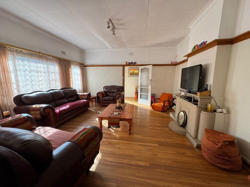 Spacious living room featuring polished hardwood flooring, a central fireplace, and classic picture rail detailing, offering a warm and inviting atmosphere.