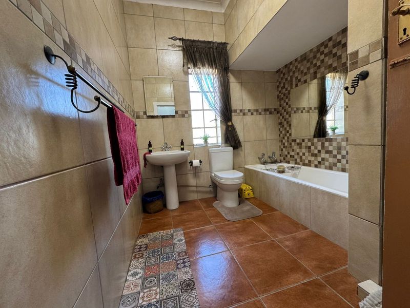 A functional bathroom featuring a pedestal basin, toilet, and built-in bathtub with neutral tiled walls and flooring.