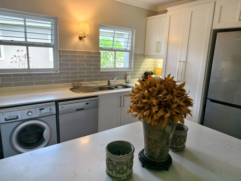 Modern kitchen featuring white shaker cabinetry, quartz countertops, subway tile backsplash, and integrated appliances including a washing machine and dishwasher.